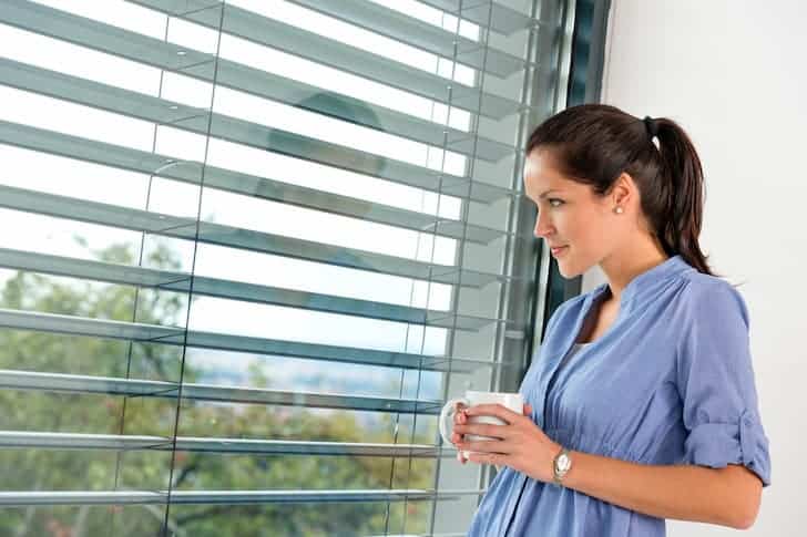 young-woman-day-dreaming-window-blinds