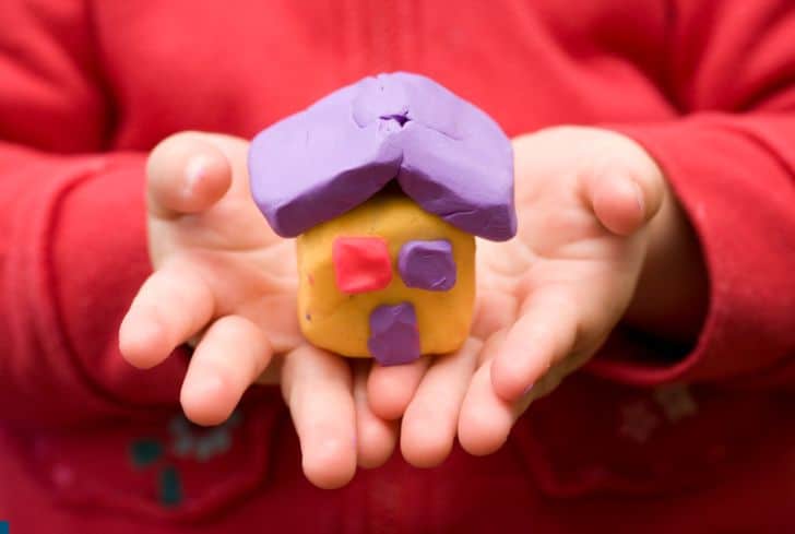 child-holding-small-play-doh-house